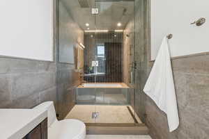 Bathroom featuring tile walls, a stall shower, and vanity