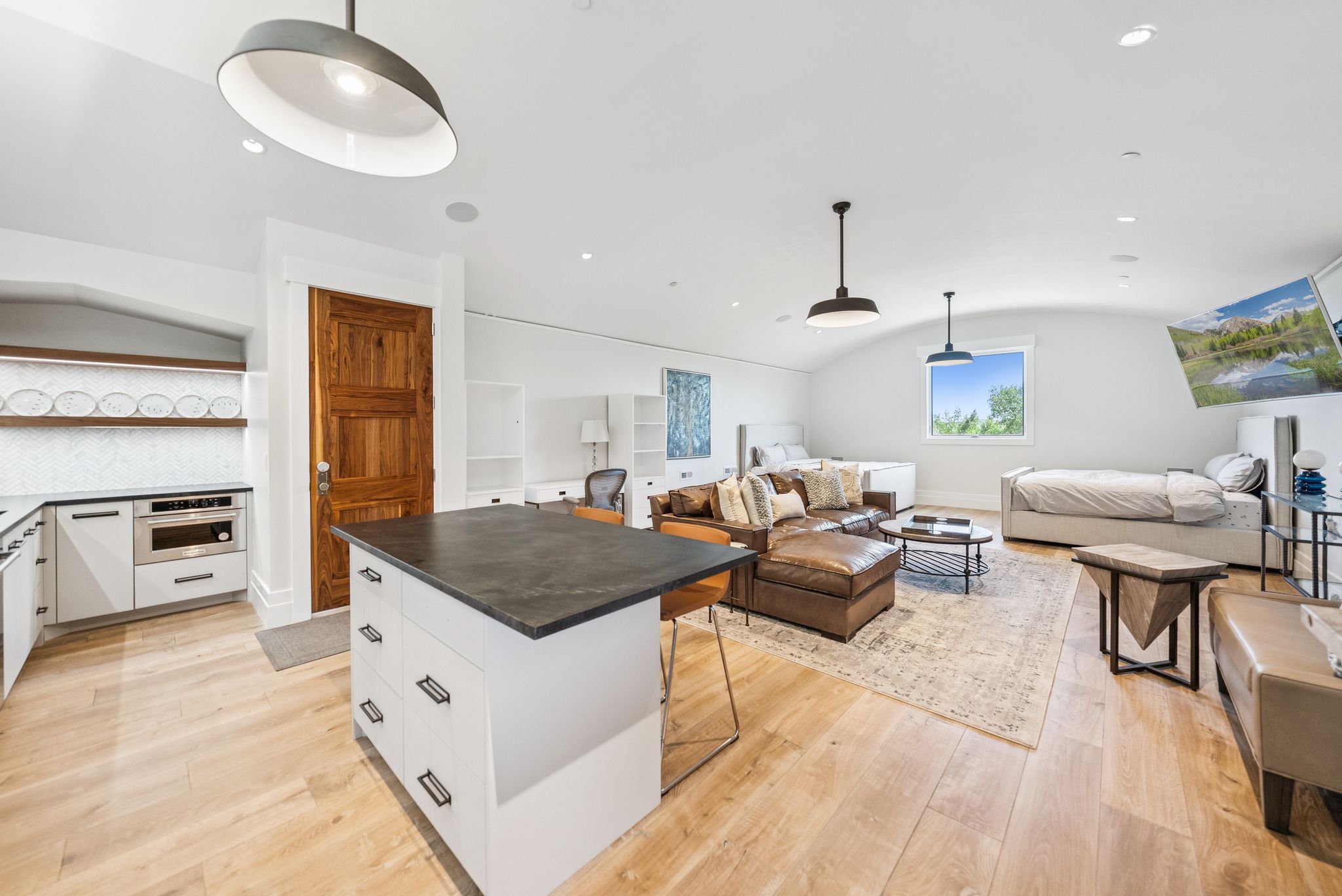Kitchen with open floor plan, oven, white cabinetry, dark countertops, and light wood-style flooring