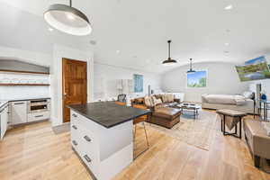 Kitchen with open floor plan, oven, white cabinetry, dark countertops, and light wood-style flooring