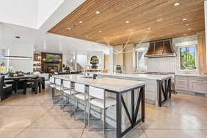 Kitchen with premium range hood, a large island with sink, wood ceiling, finished concrete flooring, and recessed lighting