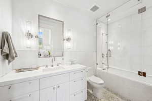Full bathroom featuring vanity, combined bath / shower with glass door, and speckle patterned floor
