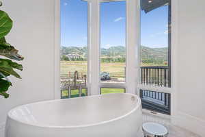 Full bath with a mountain view, plenty of natural light, and a soaking tub