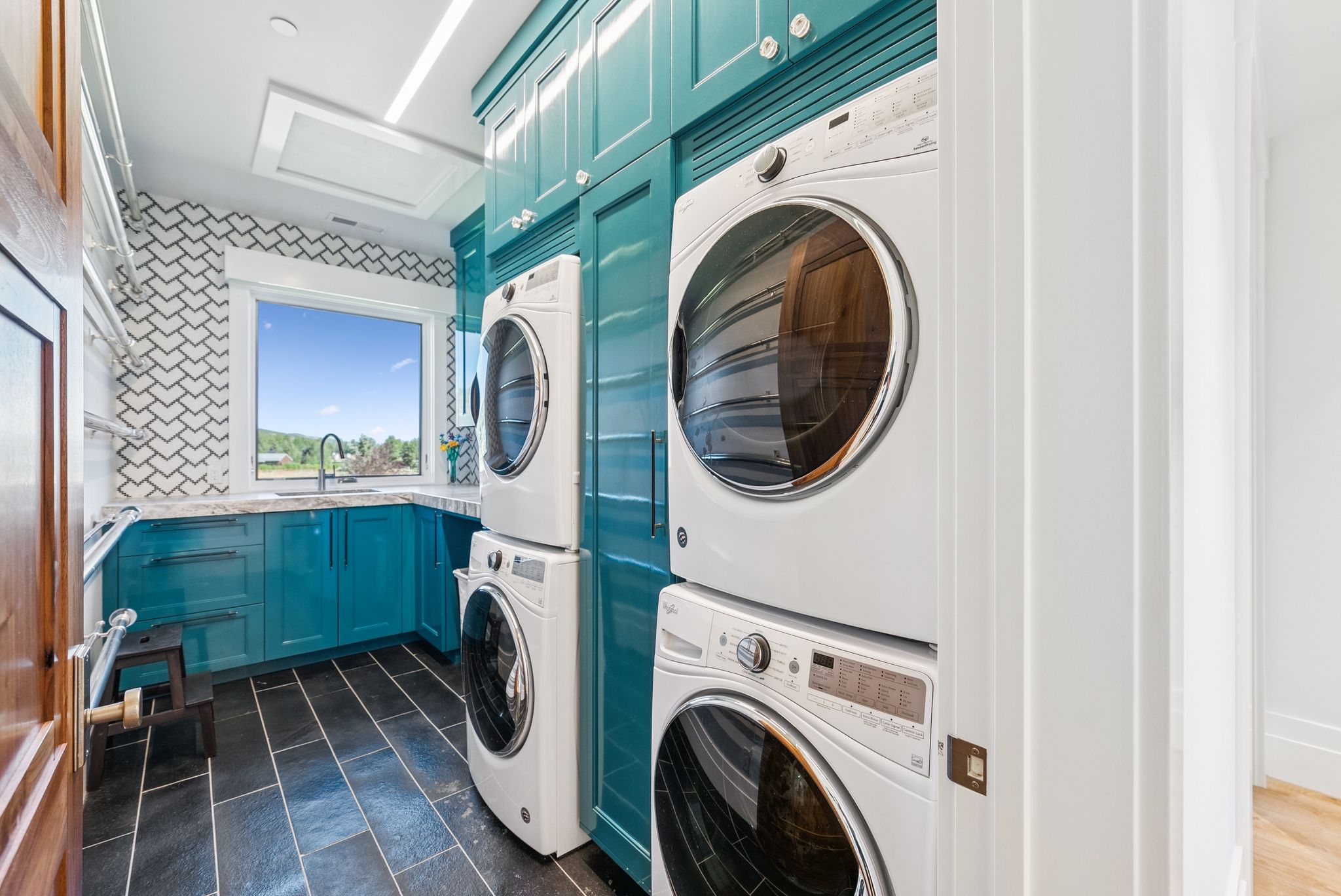 Washroom featuring cabinet space, stacked washing machine and dryer, and attic access