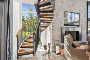 Stairs with finished concrete flooring and a warm lit fireplace