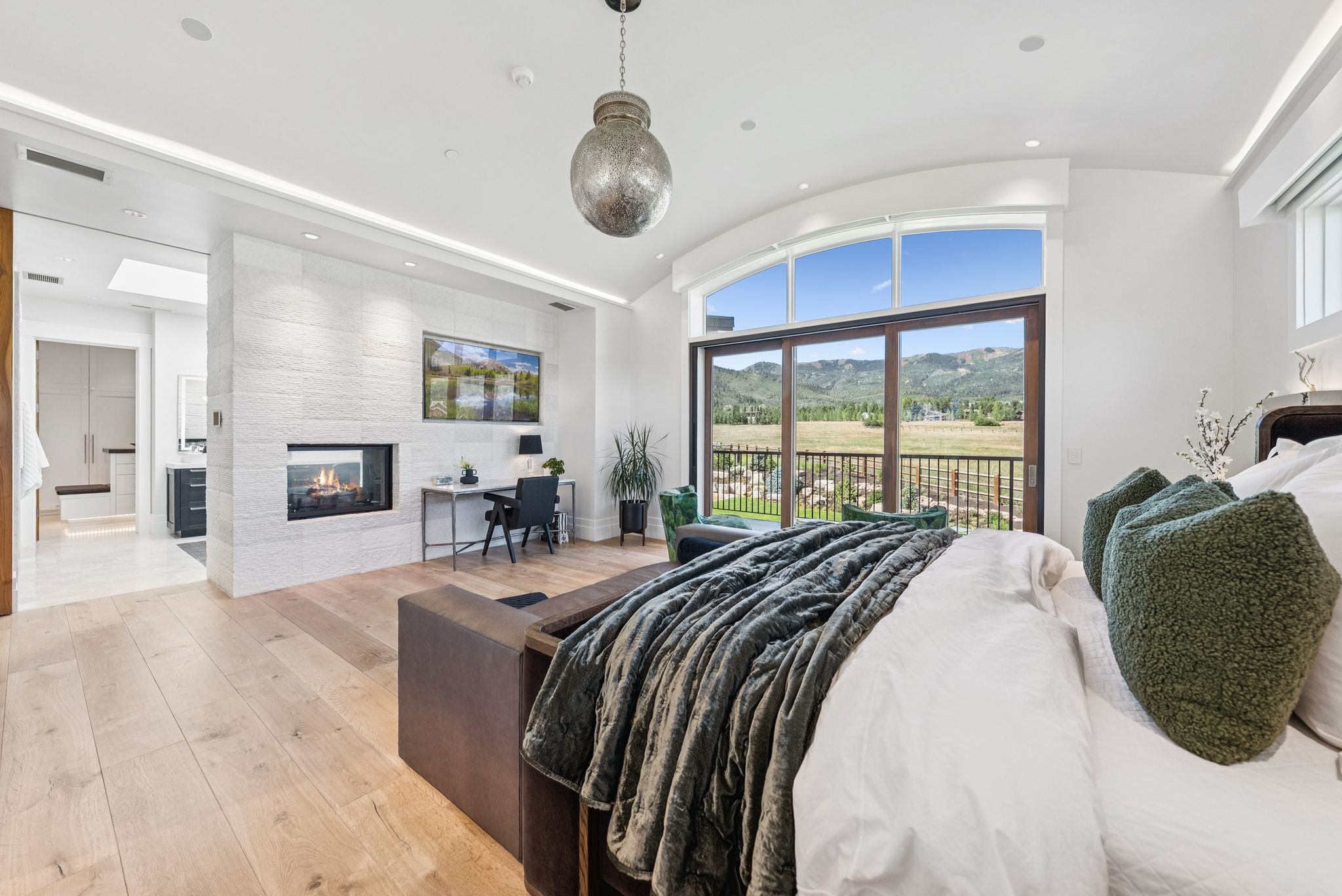 Bedroom featuring access to outside, light wood finished floors, a multi sided fireplace, vaulted ceiling, and recessed lighting