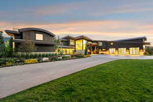 Contemporary house featuring curved driveway, a front yard, a garage, and a metal roof
