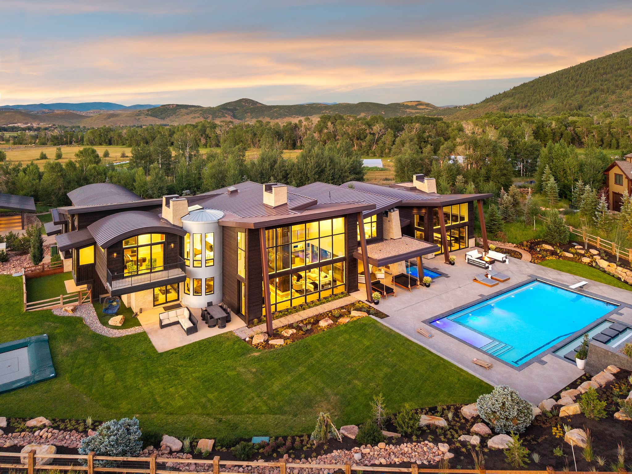 Back of house at dusk with an outdoor living space, a chimney, a balcony, a fenced backyard, and a patio
