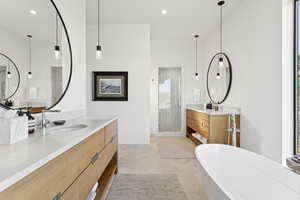 Full bath featuring a freestanding bath, two vanities, a tile shower, and recessed lighting