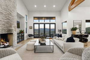 Living area with a towering ceiling, a fireplace, wood finished floors, and recessed lighting