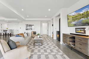 Living room with recessed lighting, a fireplace, finished concrete floors, and built in shelves