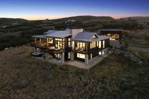 Rear view of house with a metal roof, a standing seam roof, a mountain view, a chimney, and stone siding