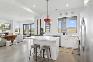 Kitchen featuring finished concrete floors, appliances with stainless steel finishes, a center island, recessed lighting, and a kitchen bar