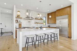 Kitchen featuring open shelves, built in fridge, backsplash, brown cabinetry, and recessed lighting