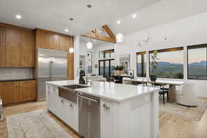 Kitchen with light wood-style flooring, stainless steel appliances, brown cabinets, backsplash, and recessed lighting