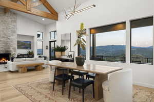 Dining area with high vaulted ceiling, a mountain view, wood finished floors, beamed ceiling, and healthy amount of natural light