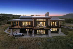 Rear view of property with a patio, a chimney, stone siding, a mountain view, and a standing seam roof