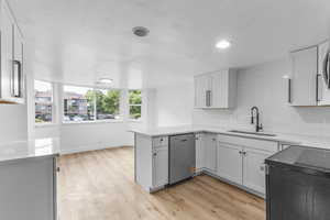 Kitchen with stove, a peninsula, light countertops, stainless steel dishwasher, and backsplash