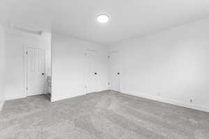 Carpeted empty room with attic access and baseboards