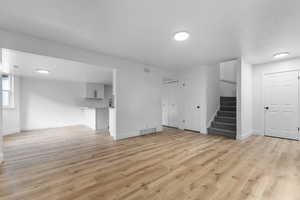 Unfurnished living room with stairway and light wood finished floors
