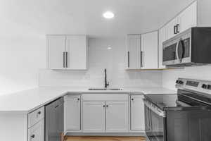 Kitchen featuring stainless steel appliances, a peninsula, tasteful backsplash, and white cabinets