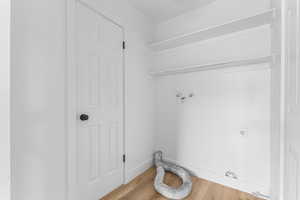 Laundry area with hookup for an electric dryer, wood finished floors, and washer hookup