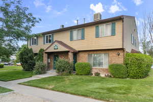 Colonial-style house with brick siding and a front lawn
