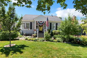 View of front of house with a front yard, a shingled roof, and a chimney