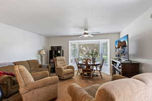 Carpeted living room with ceiling fan and baseboards