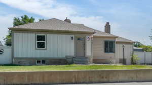 View of front of house featuring entry steps, roof with shingles, a chimney, and board and batten siding