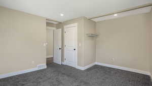 Unfurnished bedroom with dark carpet and recessed lighting