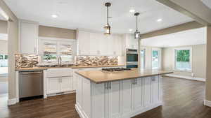 Kitchen featuring stainless steel appliances, decorative backsplash, white cabinetry, and recessed lighting