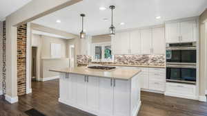 Kitchen featuring stainless steel appliances, tasteful backsplash, white cabinets, dark wood-type flooring, and recessed lighting
