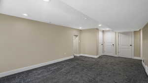 Finished below grade area featuring dark carpet, recessed lighting, and a textured ceiling