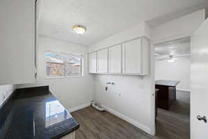 Laundry room featuring a textured ceiling, dark wood finished floors, cabinet space, a ceiling fan, and washer hookup
