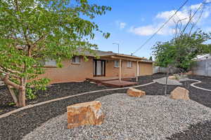 View of front of house featuring a fenced backyard, brick siding, and a deck