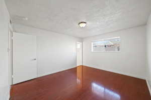 Unfurnished room with wood finished floors and a textured ceiling