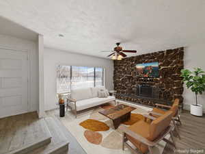 Living area featuring wood finished floors, a ceiling fan, a textured ceiling, and a fireplace