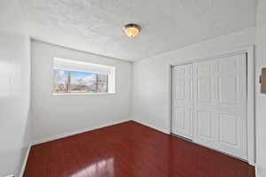 Unfurnished bedroom featuring wood finished floors, a closet, and a textured ceiling