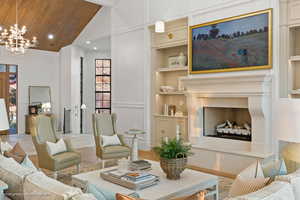 Living room with a chandelier, high vaulted ceiling, built in shelves, wood ceiling, and recessed lighting