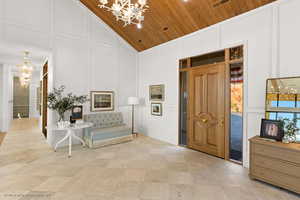 Foyer featuring a decorative wall, a chandelier, wood ceiling, and high vaulted ceiling