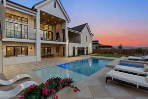 Back of property featuring a balcony, a patio, and stucco siding