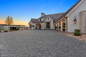 View of front of property featuring brick siding, a chimney, and decorative driveway