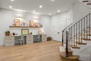 Office area with built in desk, light wood-style floors, and recessed lighting