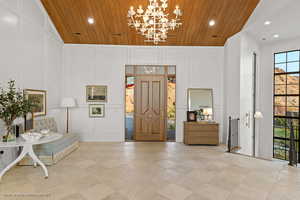 Entryway with a decorative wall, wooden ceiling, recessed lighting, a chandelier, and high vaulted ceiling