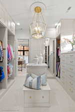 Spacious closet with light carpet and a chandelier
