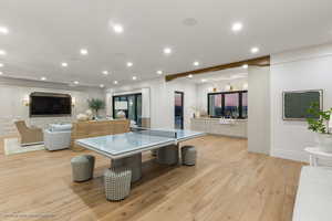 Recreation room with light wood-style floors and recessed lighting