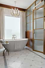Full bathroom with a chandelier and a freestanding tub