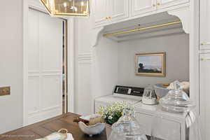 Washroom with washing machine and clothes dryer, cabinet space, and a chandelier