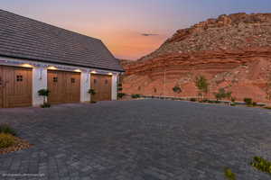 Garage at dusk featuring a mountain view and decorative driveway
