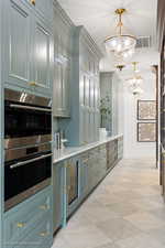 Bar area with a chandelier, double oven, decorative light fixtures, and beverage cooler